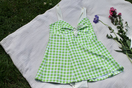 Apple green Gingham swim dress - photographed on a white picnic blanket with grass background.